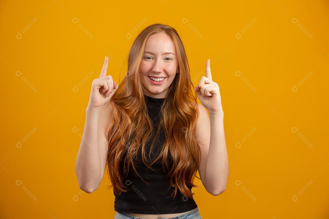 Uma garota ruiva em fundo de estúdio amarelo oferece oportunidades