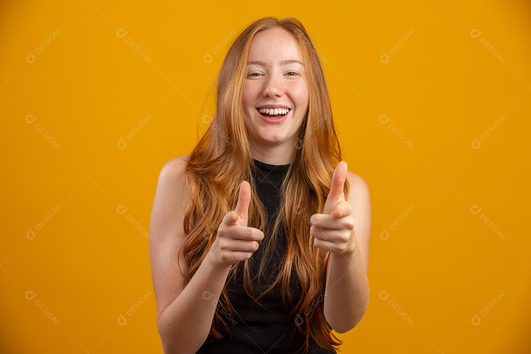 Uma garota ruiva em fundo de estúdio amarelo oferece oportunidades