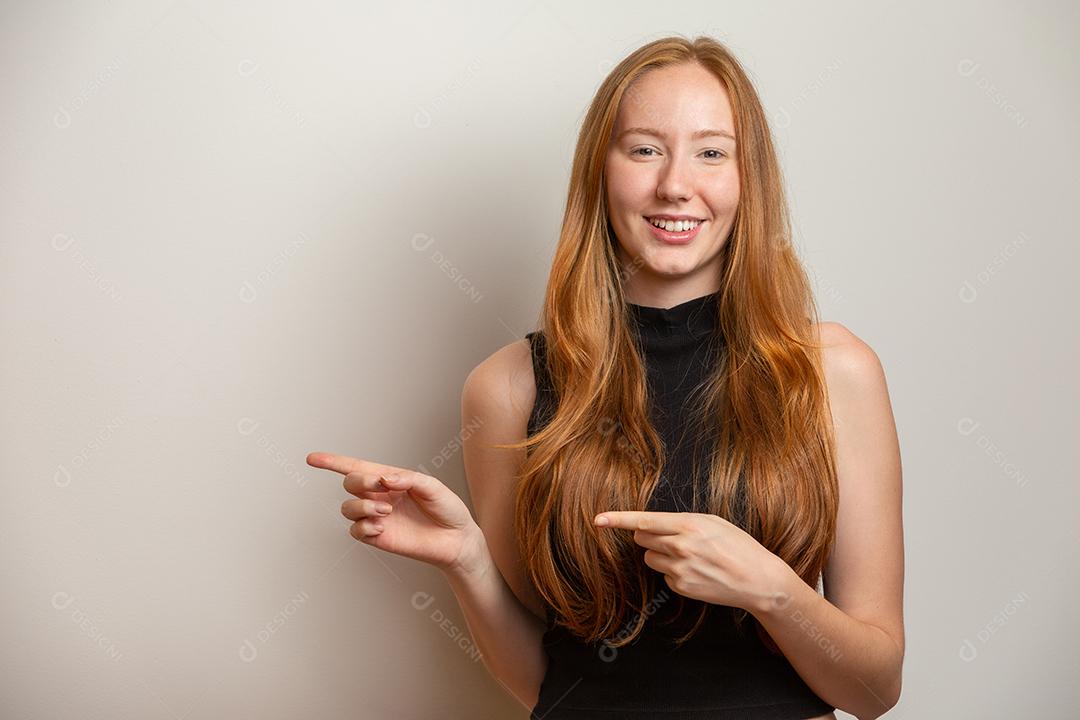 Uma garota ruiva no fundo do estúdio branco oferece oportunidades