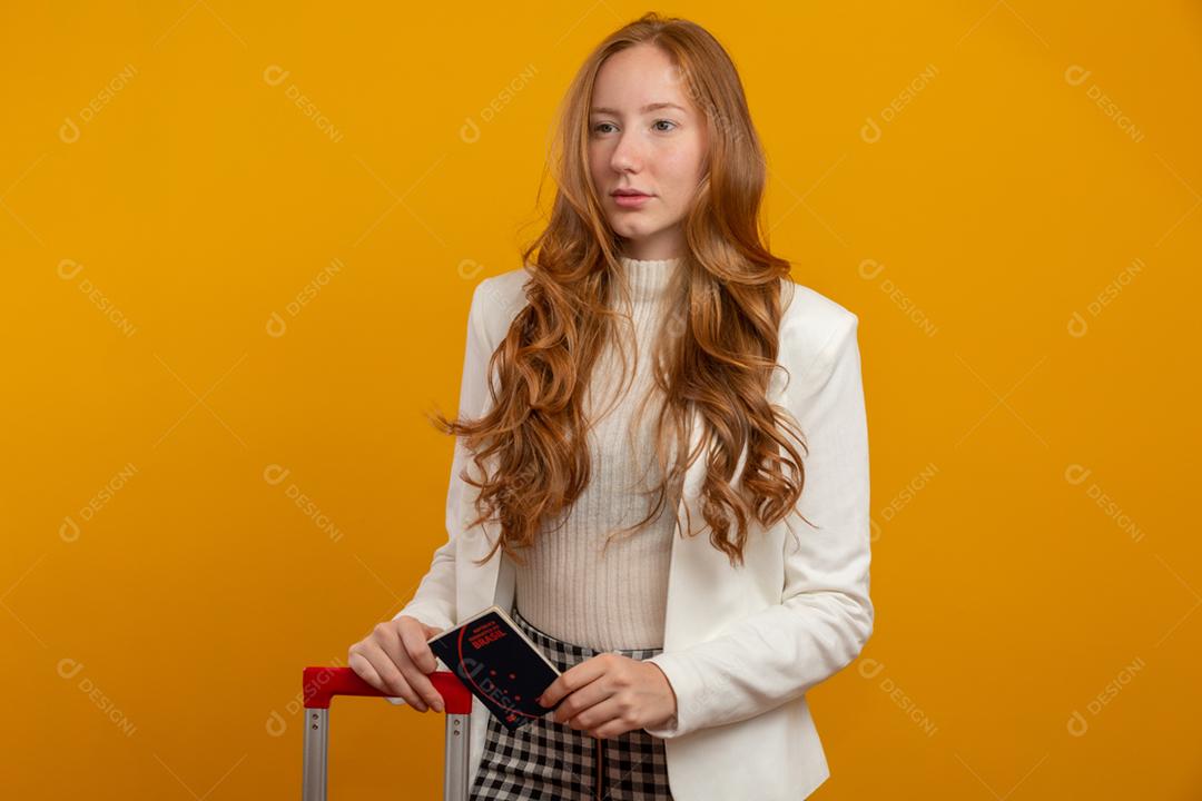 Linda ruiva de cabelos cacheados em viagens. Próxima viagem. Garota segurando passaporte brasileiro. Em amarelo.