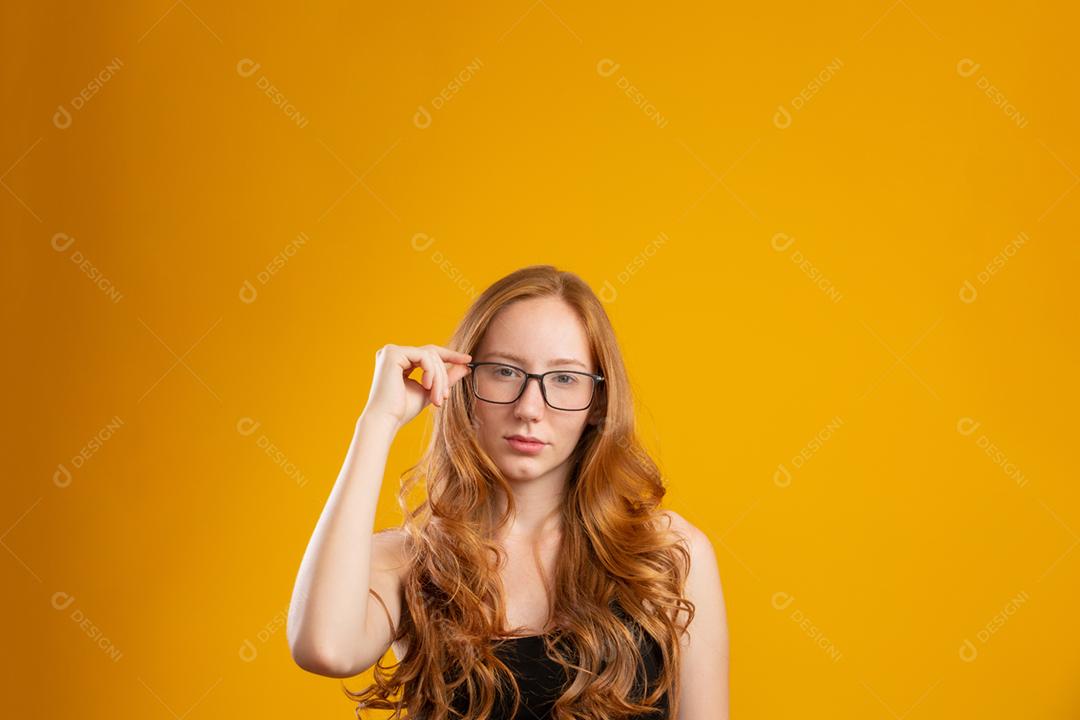 Mulher jovem e bonita ruiva com cabelo encaracolado feliz com seus óculos. Conceito de cuidados com os olhos