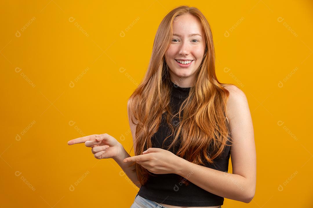 Uma garota ruiva em fundo de estúdio amarelo oferece oportunidades
