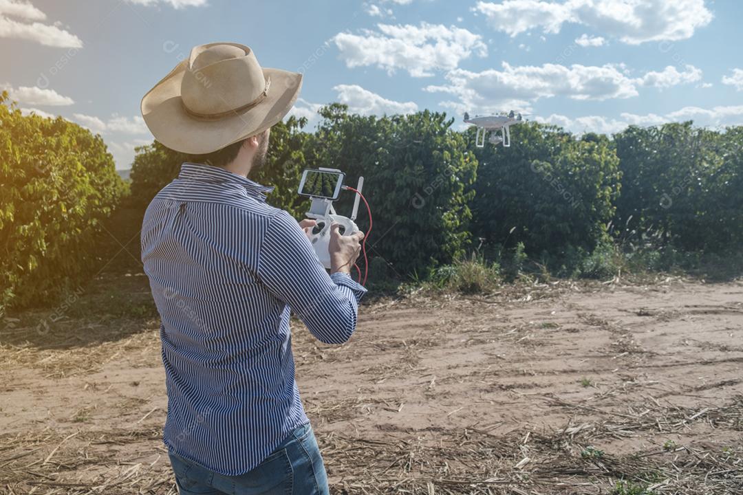 Jovem agricultor analisando uma plantação de café através de um drone. Agricultor usando drone