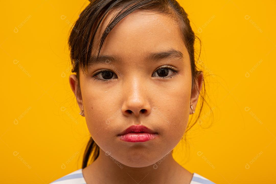 Linda garota asiática sentada no fundo amarelo. Feliz menina asiática sorrindo.