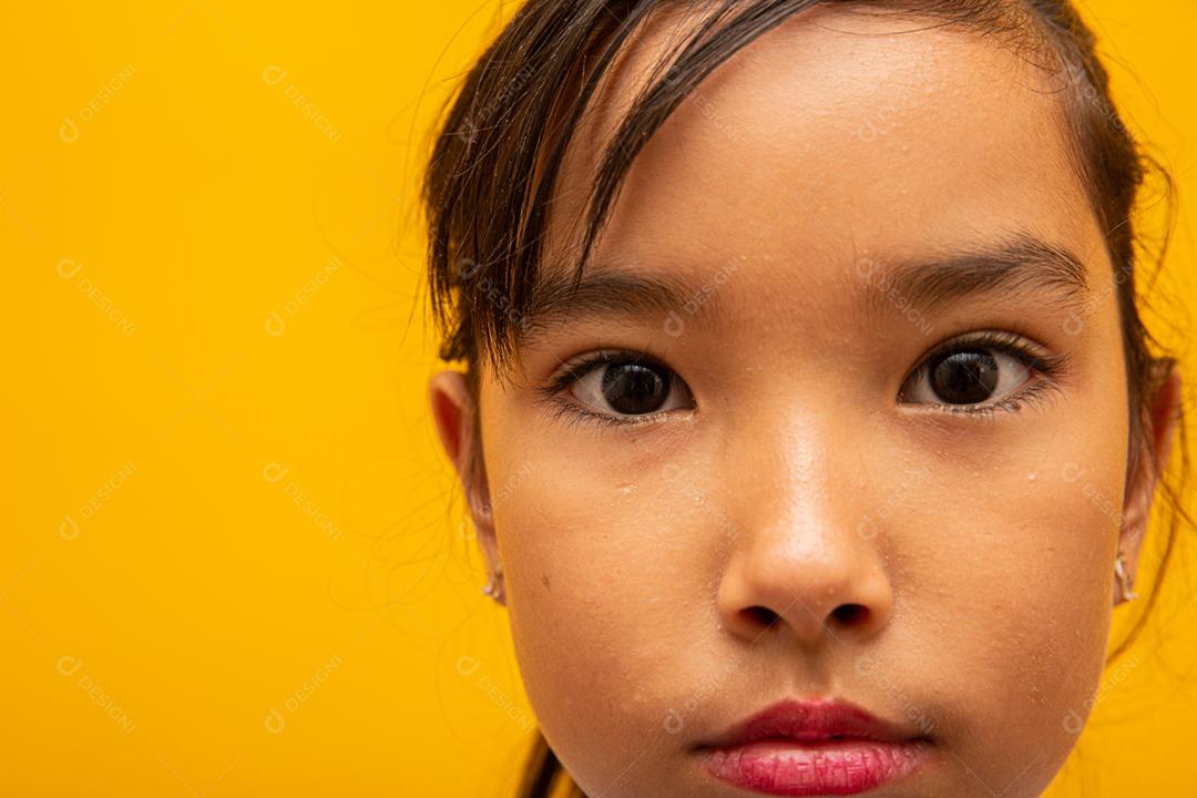 Linda garota asiática sentada no fundo amarelo. Feliz menina asiática sorrindo.