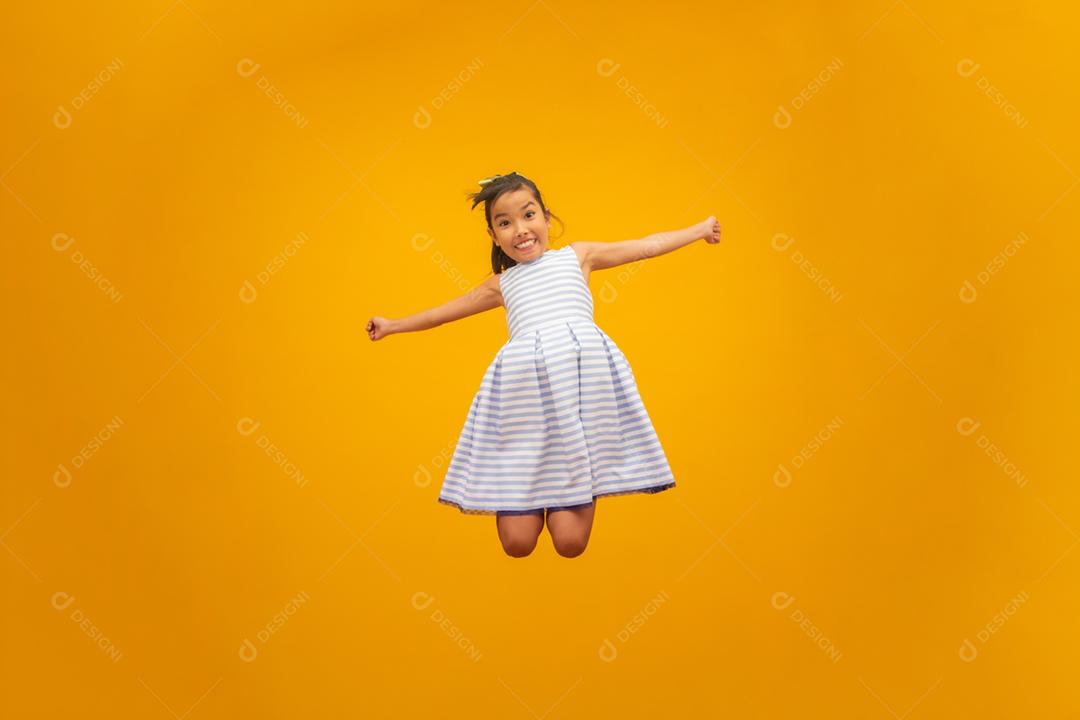 Linda garota asiática sentada no fundo amarelo. Feliz menina asiática sorrindo.