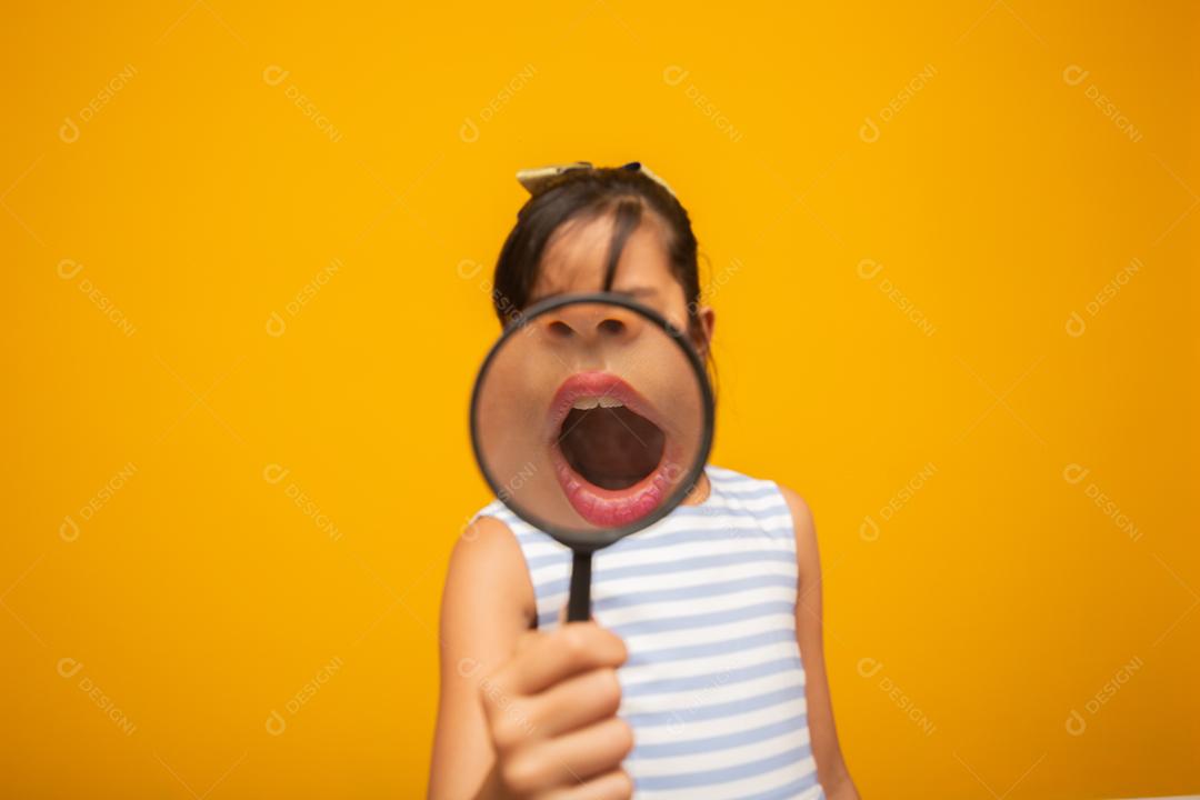 Retrato de criança asiática feliz com lupa.