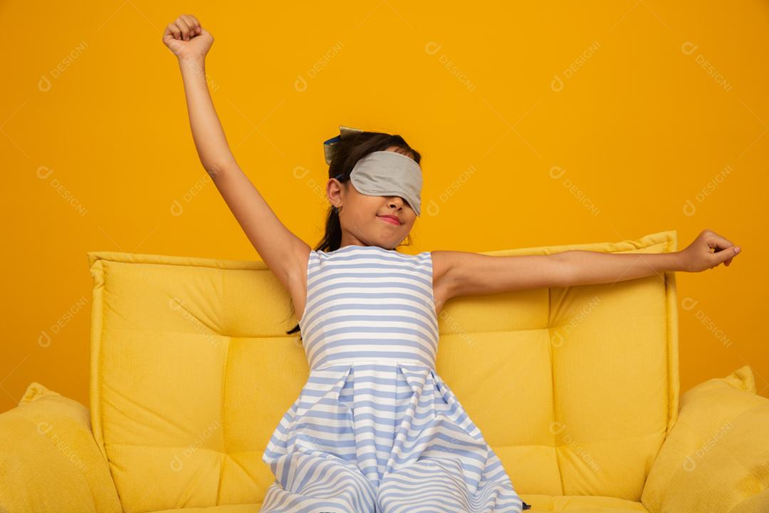 Criança asiática dormindo em um sofá com máscara de dormir.