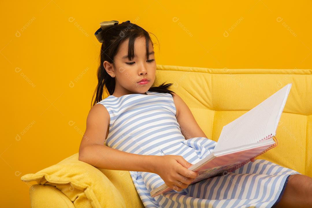 Garota jovem estudante asiática segurando livros sobre fundo amarelo