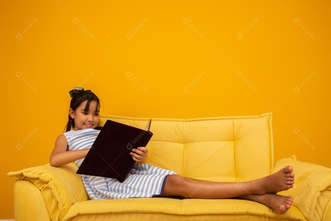 Garota jovem estudante asiática segurando livros sobre fundo amarelo