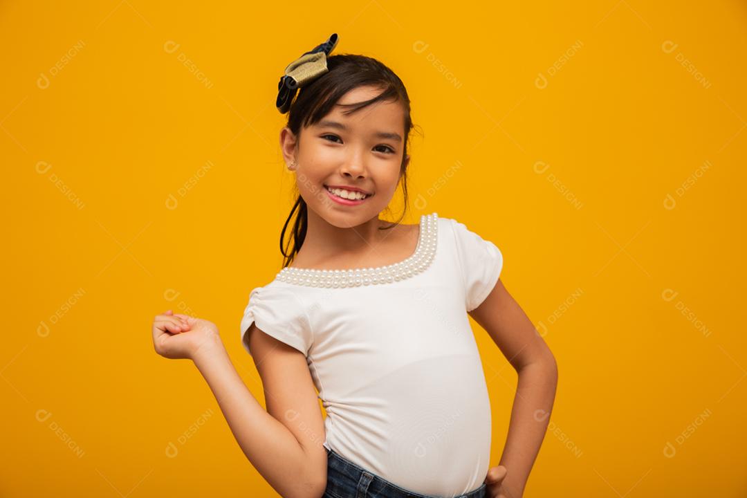 Linda garota asiática sentada no fundo amarelo. Feliz menina asiática sorrindo.