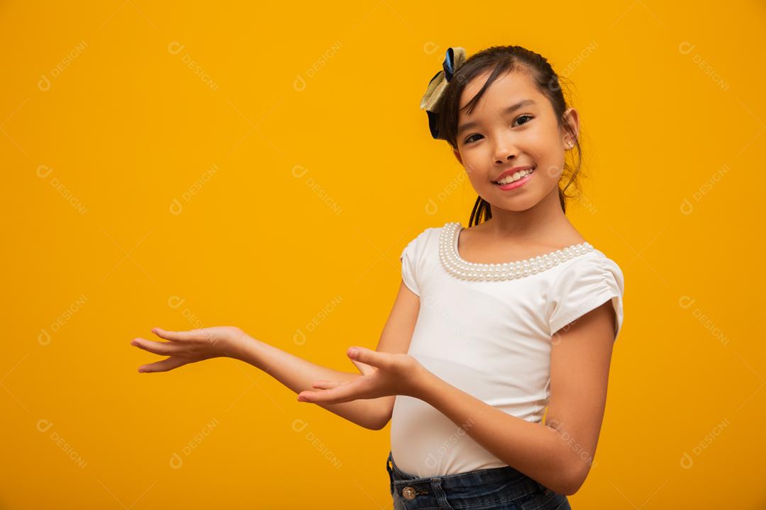 Linda garota asiática sentada no fundo amarelo. Feliz menina asiática sorrindo.