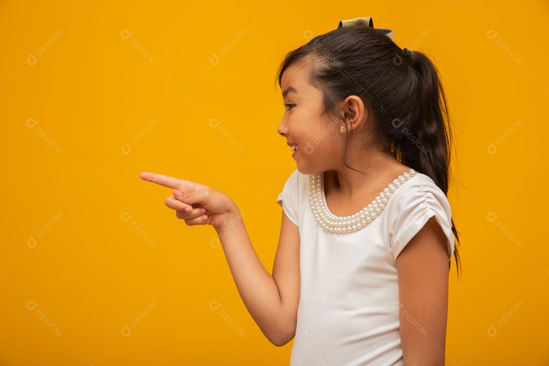 Linda garota asiática sentada no fundo amarelo. Feliz menina asiática sorrindo.