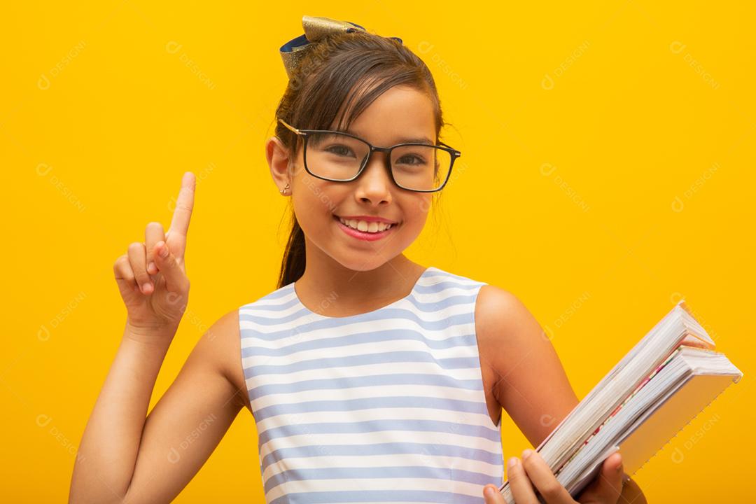 Garota jovem estudante asiática segurando livros sobre fundo amarelo