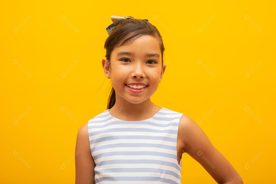 Linda garota asiática sentada no fundo amarelo. Feliz menina asiática sorrindo.