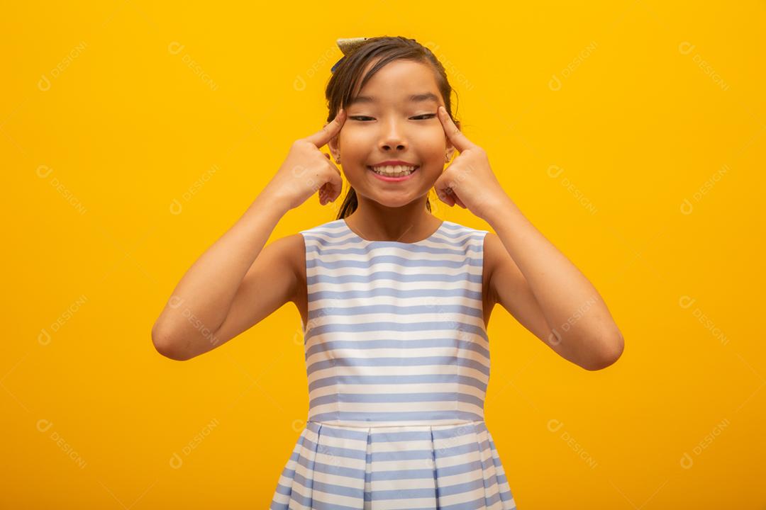 Linda garota asiática sentada no fundo amarelo. Feliz menina asiática sorrindo.