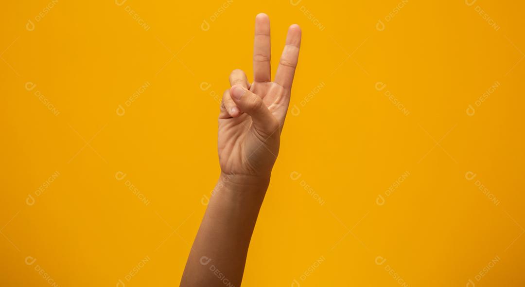 Mulher mostra sinal de vitória em fundo amarelo