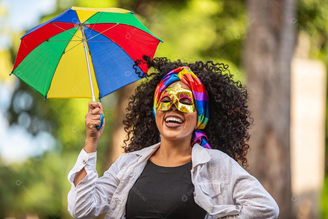Mulher jovem de cabelo encaracolado comemorando a festa de carnaval brasileira com guarda-chuva de Frevo na rua.