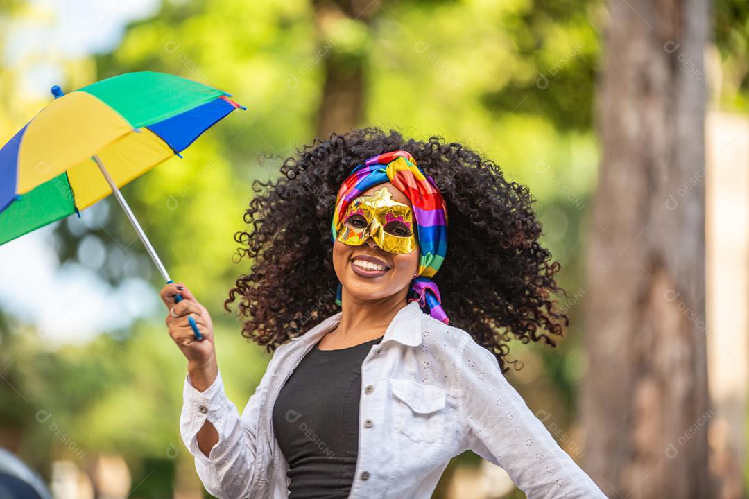 Young woman with curly hair celebrating Brazilian carnival party with Frevo umbrella in the street.