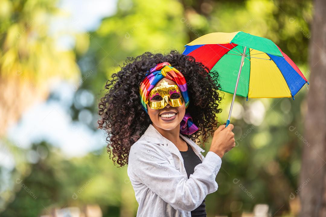 Mulher jovem de cabelo encaracolado comemorando a festa de carnaval brasileira com guarda-chuva de Frevo na rua.