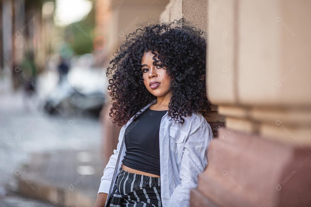 Linda garota brasileira com cabelo encaracolado na rua. A vida nas grandes cidades.