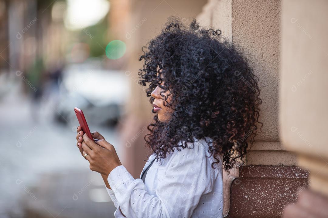 Linda garota brasileira com cabelo encaracolado na rua. A vida nas grandes cidades.
