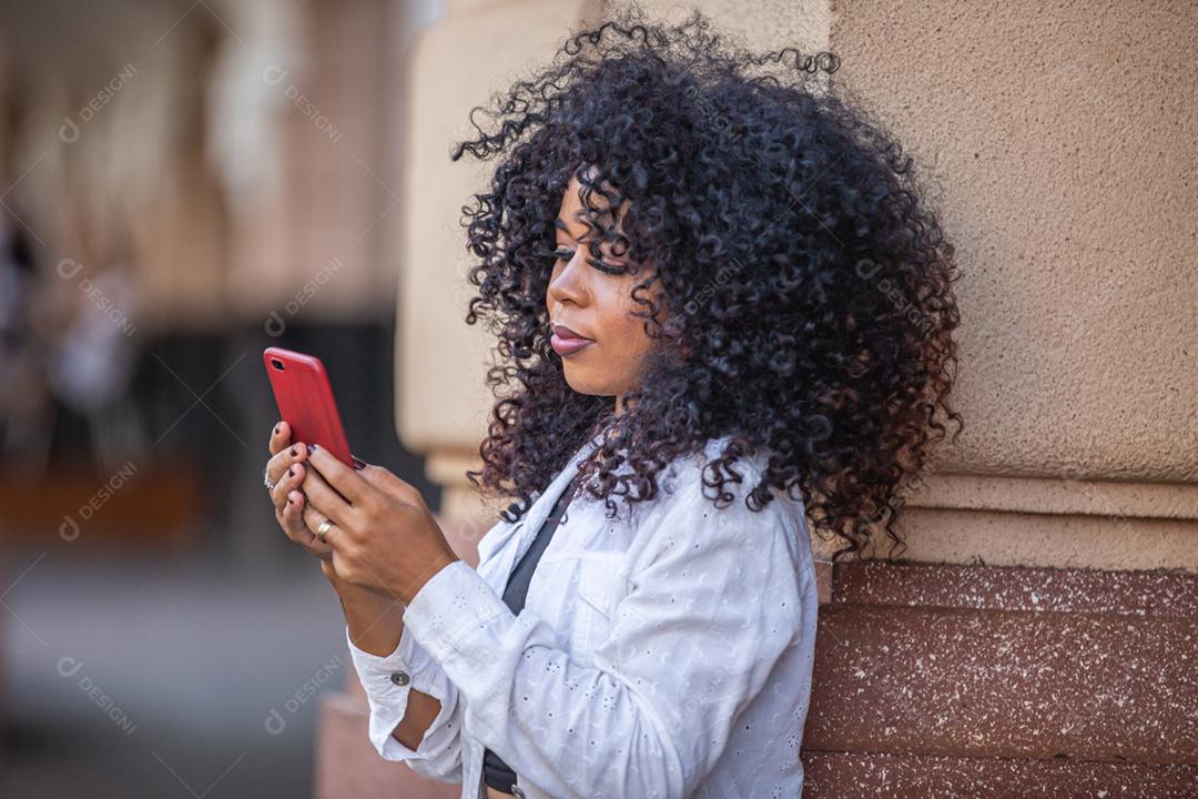 Linda garota brasileira com cabelo encaracolado na rua. A vida nas grandes cidades.