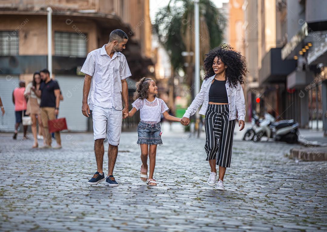 Família tradicional brasileira. Pai e mãe caminhando com sua filha.