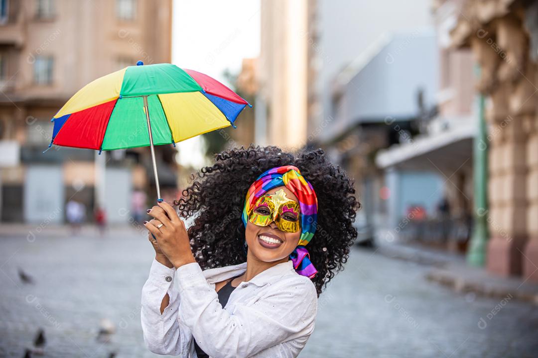 Festa carnavalesca. Mulher brasileira de cabelo encaracolado fantasiada soprando confete