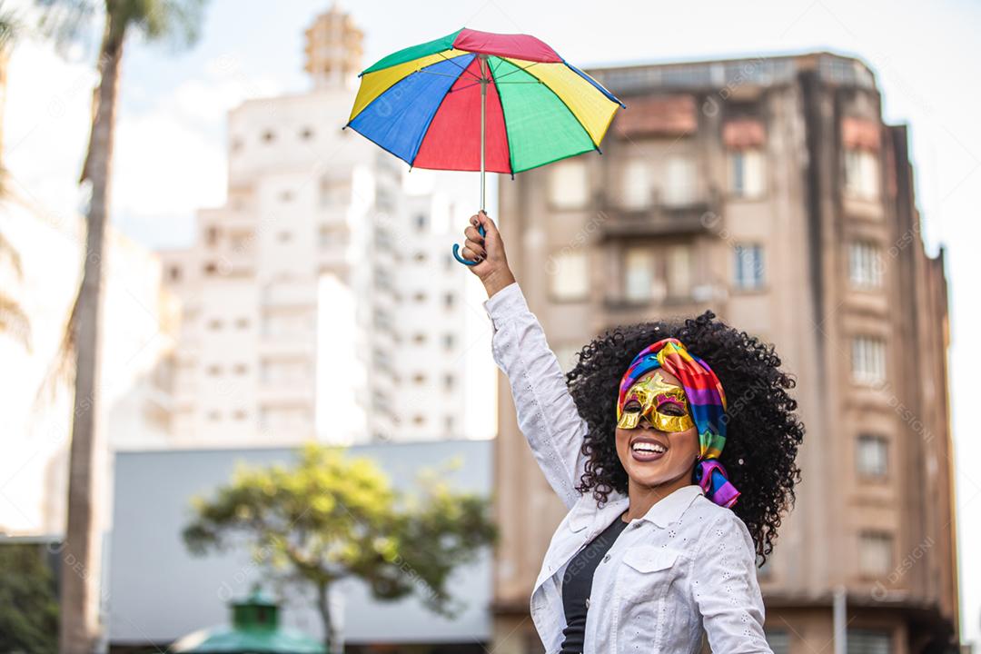 Festa carnavalesca. Mulher brasileira de cabelo encaracolado fantasiada soprando confete