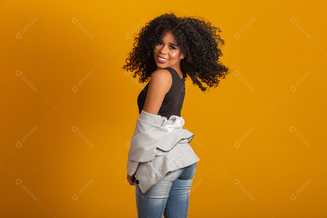 Jovem afro-americana com cabelos cacheados, olhando para a câmera e sorrindo. Linda garota