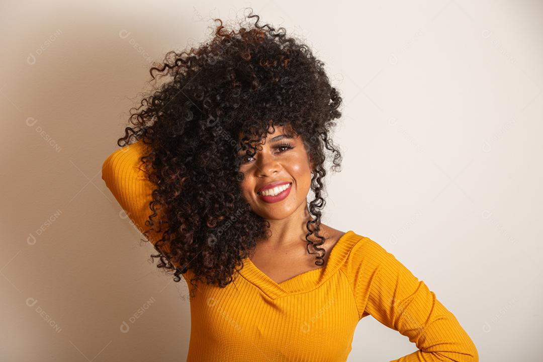 Jovem afro-americana com cabelos cacheados, olhando para a câmera e sorrindo. Linda garota