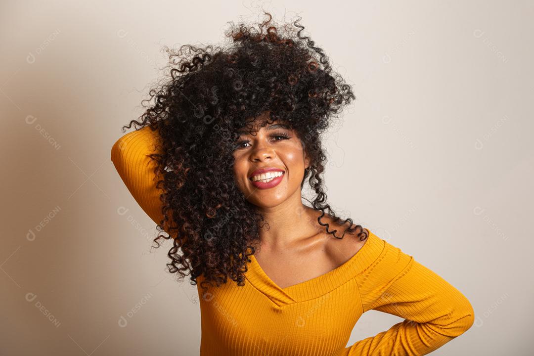 Jovem afro-americana com cabelos cacheados, olhando para a câmera e sorrindo. Linda garota