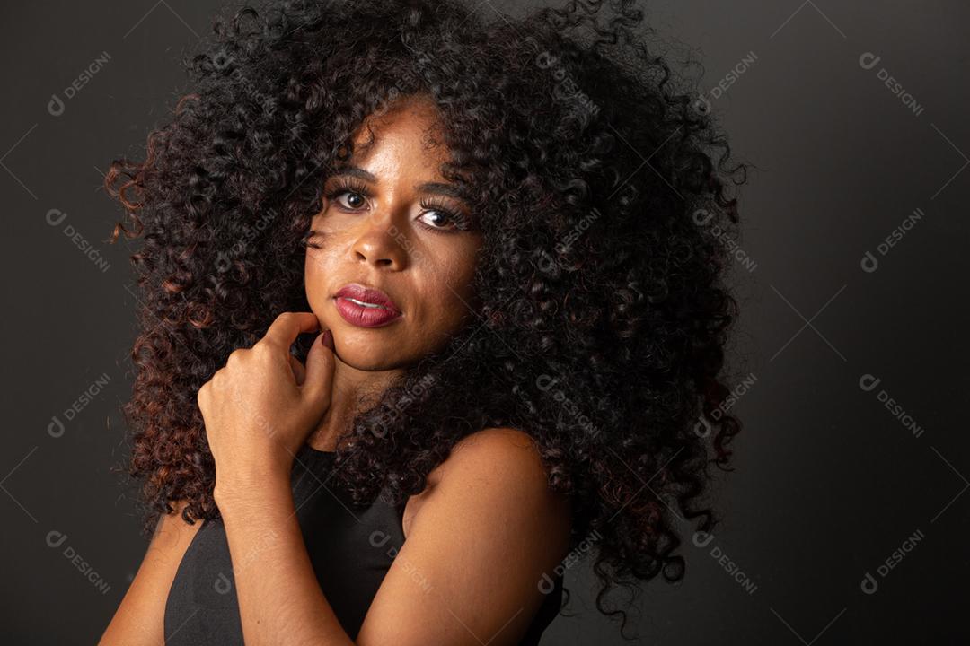 Jovem afro-americana com cabelos cacheados, olhando para a câmera e sorrindo. Linda garota