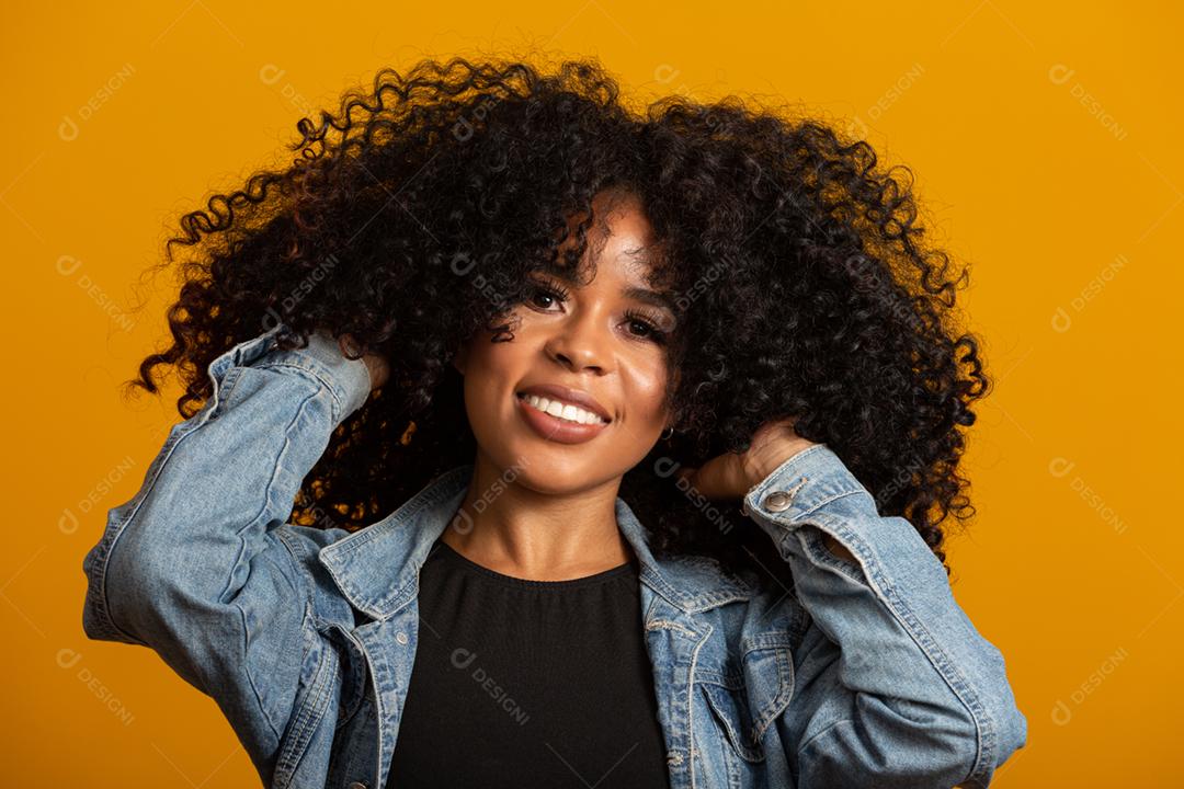 Jovem afro-americana com cabelos cacheados, olhando para a câmera e sorrindo. Linda garota