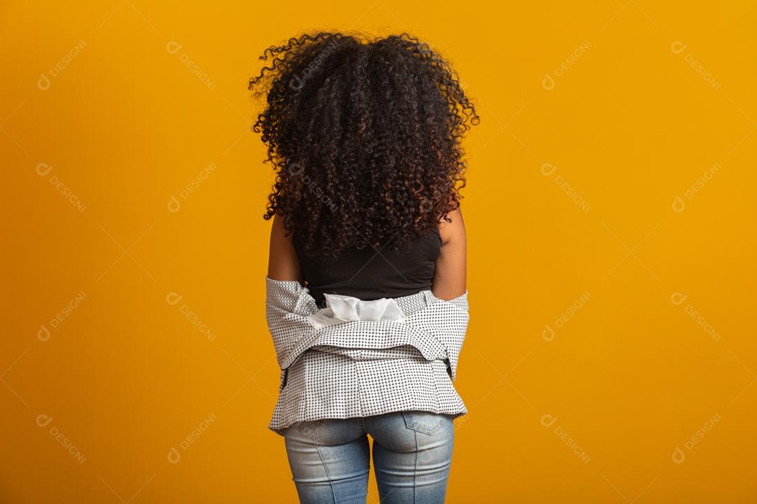 Jovem negra nas costas com penteado afro em fundo amarelo. Garota com penteado africano. Tiro de estúdio.