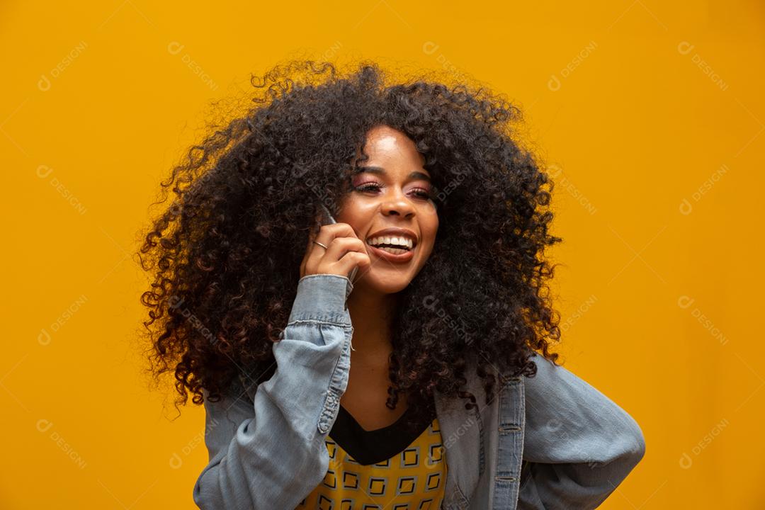Linda garota falando ao telefone. Comunicando-se ao telefone em fundo amarelo.