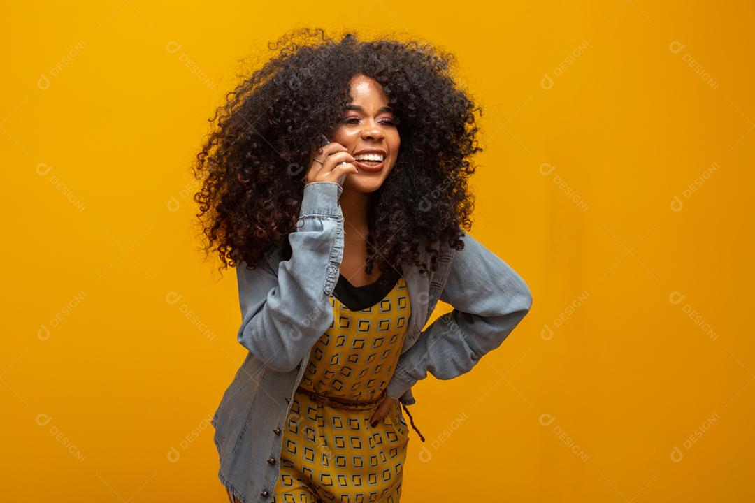 Linda garota falando ao telefone. Comunicando-se ao telefone em fundo amarelo.