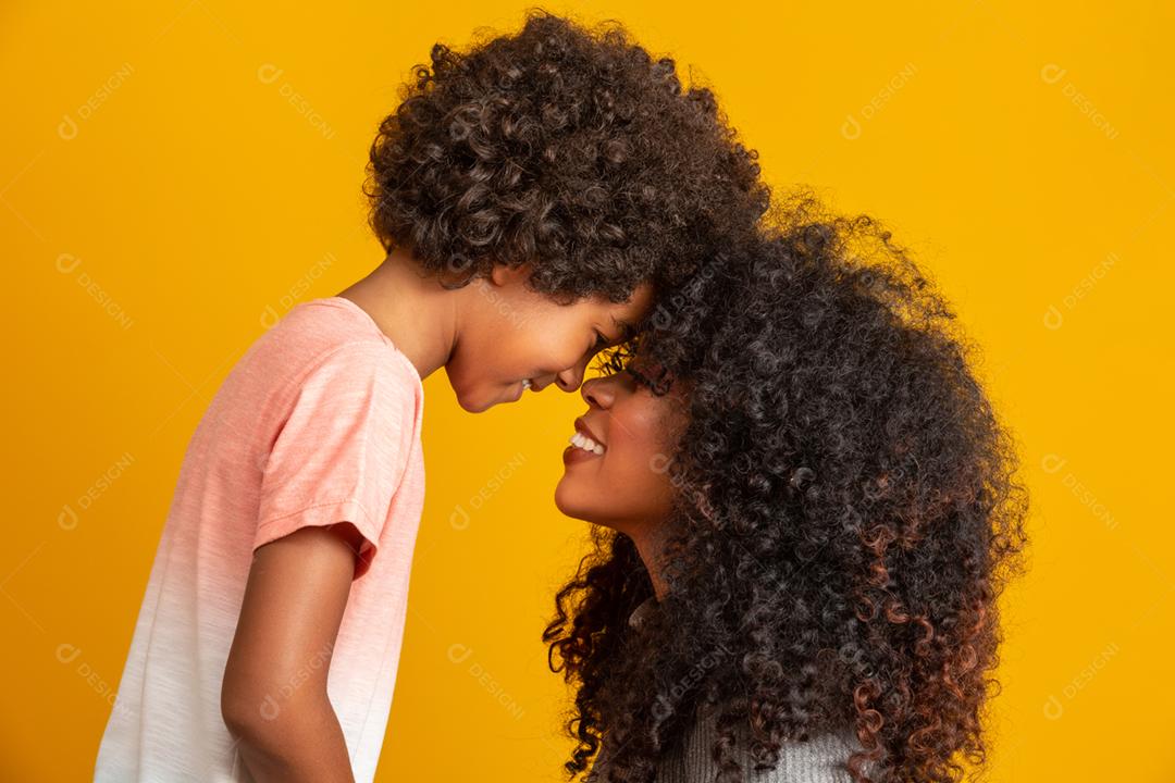 Retrato de jovem mãe afro-americana com filho da criança. Fundo amarelo. família brasileira.