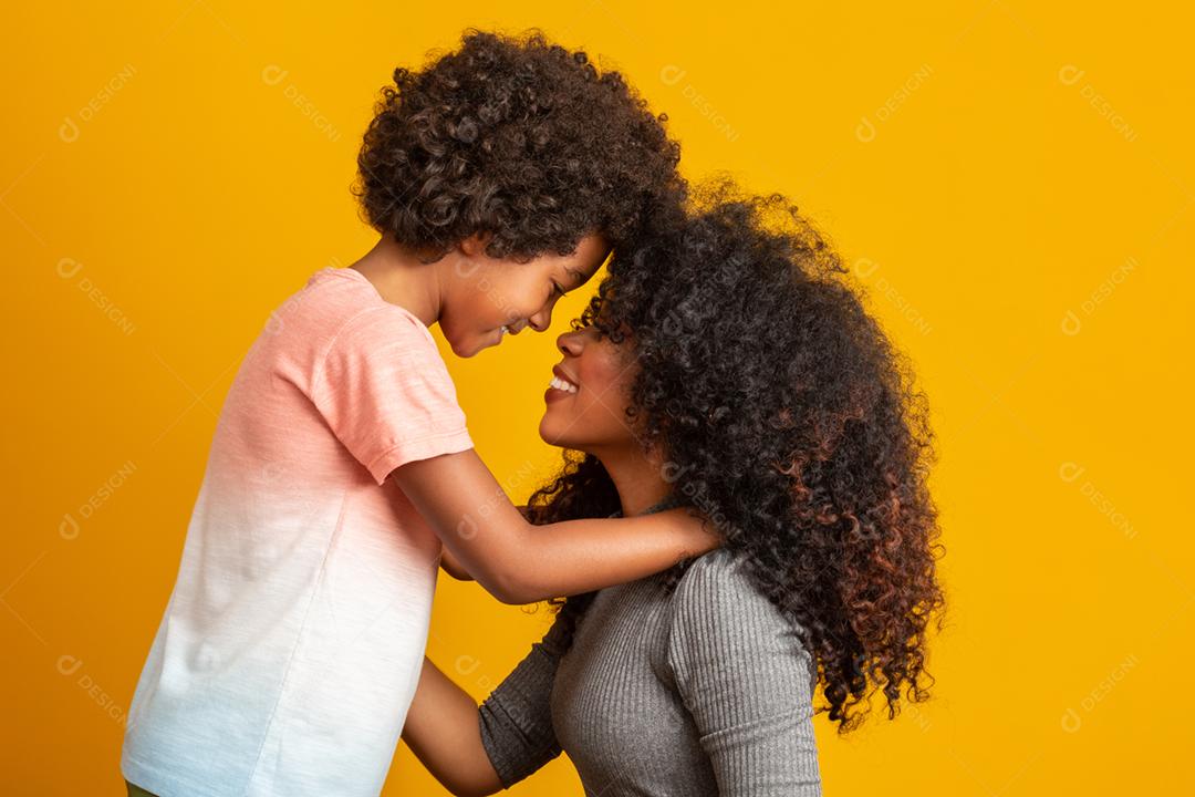 Retrato de jovem mãe afro-americana com filho da criança. Fundo amarelo. família brasileira.