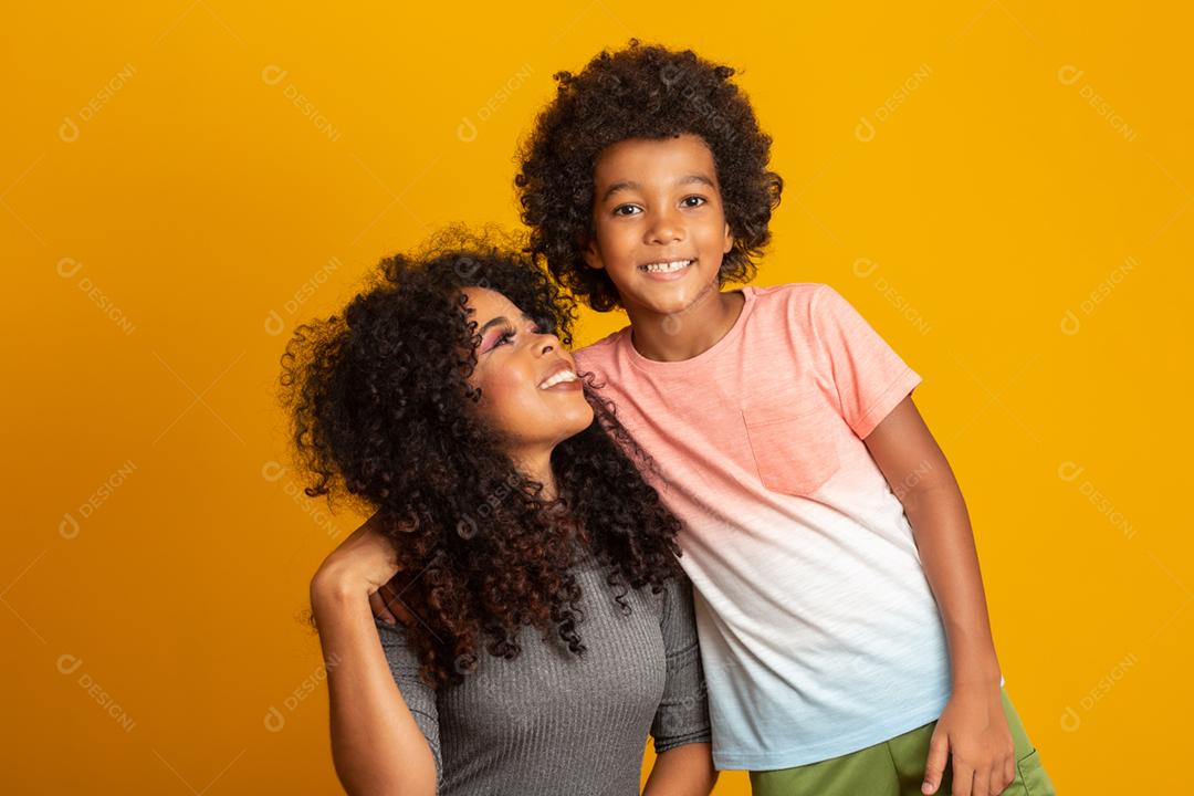 Retrato de jovem mãe afro-americana com filho da criança. Fundo amarelo. família brasileira.