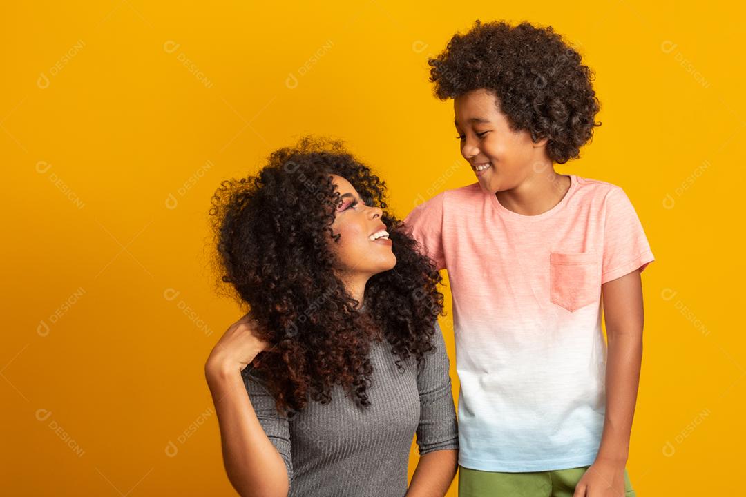 Retrato de jovem mãe afro-americana com filho da criança. Fundo amarelo. família brasileira.