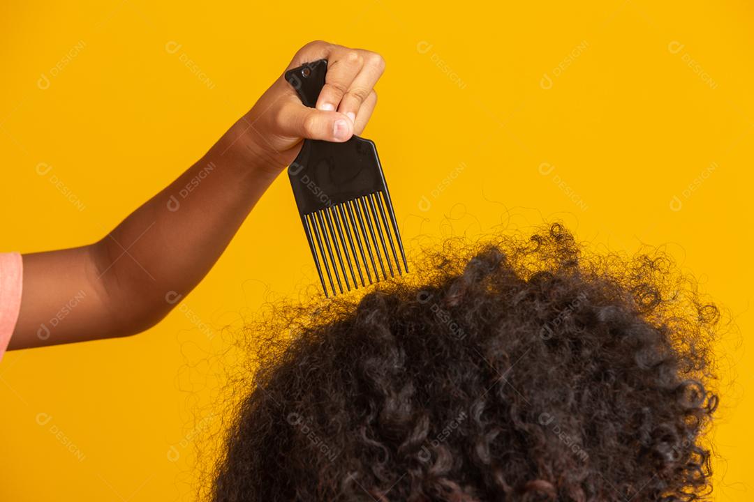 Jovens afro-americanos penteando o cabelo isolado. Garfo para pentear cabelos cacheados