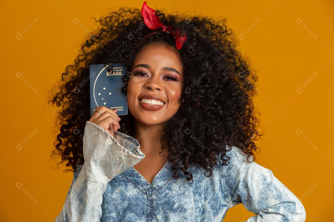 Linda garota de cabelos cacheados segurando um cartão de trabalho. Em fundo amarelo.