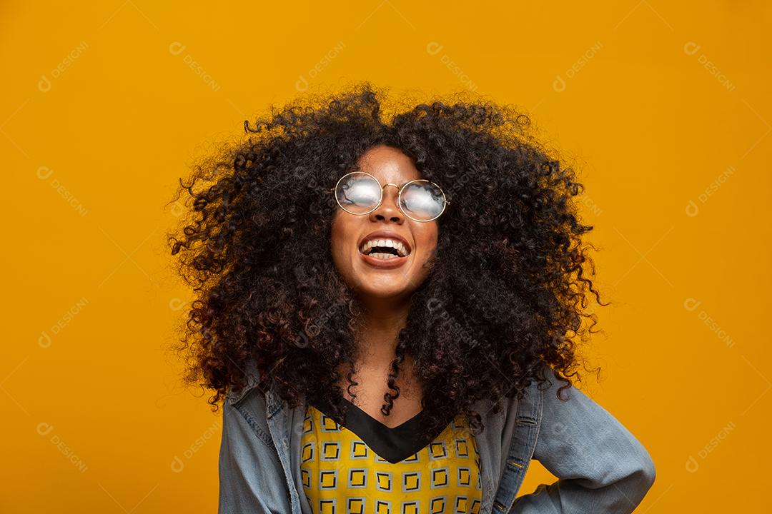 Retrato da beleza do americano africano com óculos e penteado afro em um fundo amarelo. jovem brasileira.