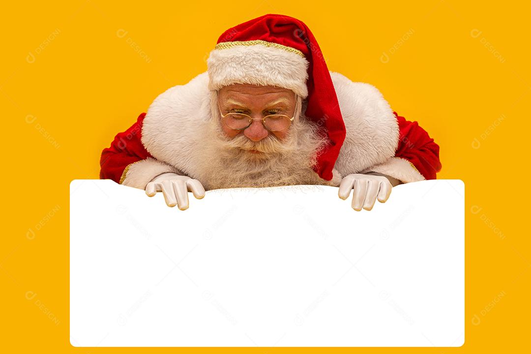 Feliz Papai Noel olhando por trás do sinal em branco isolado em fundo amarelo