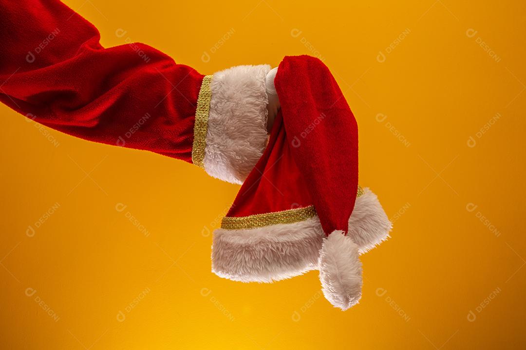Mão segurando o chapéu vermelho de Papai Noel de Natal. Papai Noel segurando seu boné.