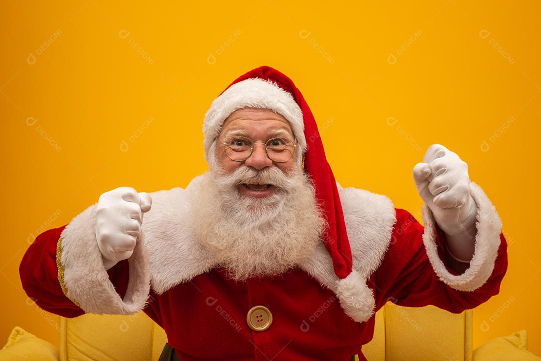 Papai Noel sentado em um sofá amarelo sobre fundo amarelo com espaço de cópia. Sofá amarelo.