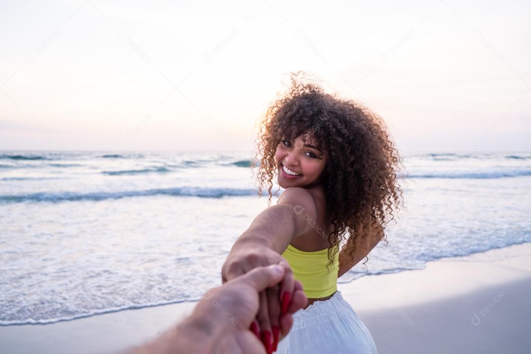 Menina segurando a mão masculina e correndo na praia tropical exótica para o oceano.
