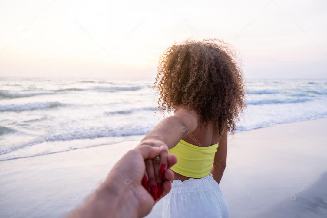 Menina segurando a mão masculina e correndo na praia tropical exótica para o oceano.